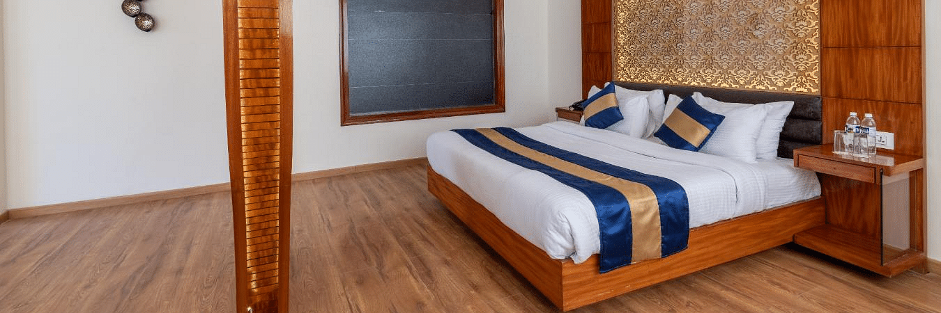 Image of the hotel bedroom with a king size bed and wooden furnishing  | DLS Serenity Resort and Spa